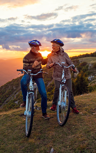 older couple riding bikes with sun setting life insurance options jb retirement strategies florida